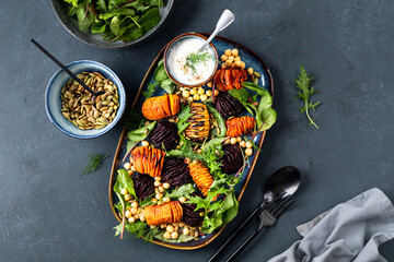 Root vegetables roast until soft in the center and crispy with chickpeas, pumpkin seeds and fresh lettuce leaves. Healthy fresh salad