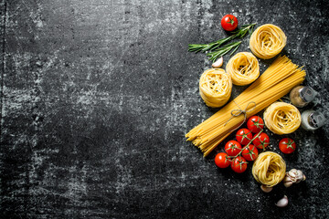 Raw tagliatelle and spaghetti with spices, tomatoes and rosemary.