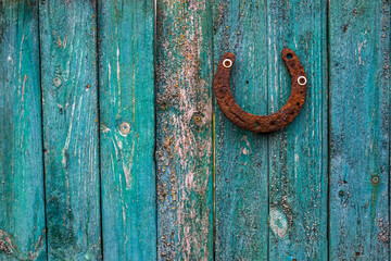 A rusty horseshoe on a wooden turquoise fence made of old weathered boards. Luck Concept