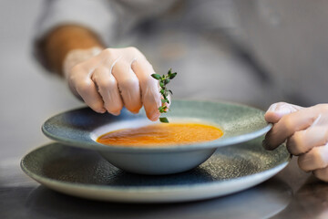 food cooking, profession and people concept - close up of male chef with thyme serving plate of...