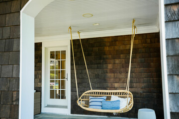 Outdoor wicker swing with cushions on back patio