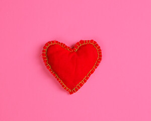 A bright red fabric heart on a magenta background. Flat lay