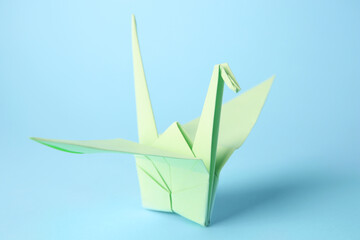 Fototapeta premium Origami art. Handmade paper crane on light blue background, closeup