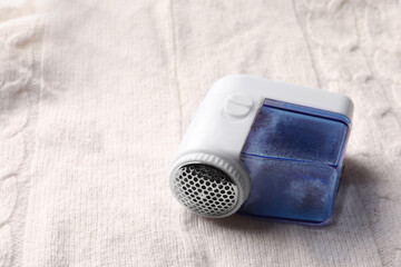 Fabric shaver with fuzz on knitted cloth, closeup. Space for text