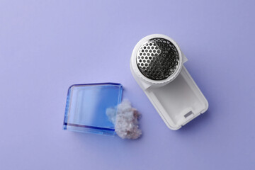 Fabric shaver with fuzz on lilac background, flat lay
