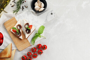 Fototapeta na wymiar Delicious sandwiches with cream cheese, anchovies and tomatoes on light grey table, flat lay. Space for text