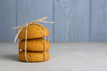 Delicious oatmeal cookies tied with twine on white table. Space for text