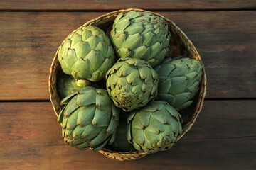 Obraz premium Tasty fresh raw artichokes on wooden table, top view