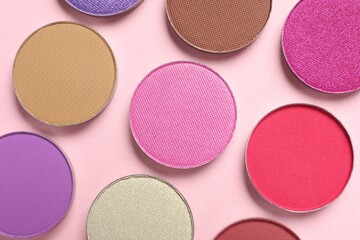 Different beautiful eye shadows on pink background, flat lay