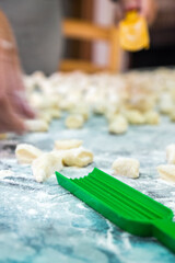 A lady cooking homemade gnocchi for lunch. The green toold to make then is in the foreground