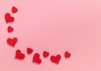 Festive frame with red wooden hearts on a pink background. Valentines day concept. Top view. Cop y space.