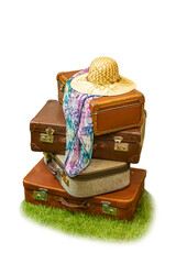 Vier braune Koffer mit Sonnenhut und Schal auf einer Wiese - obrazy, fototapety, plakaty