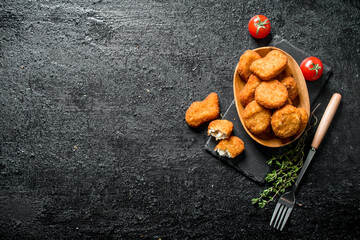 Chicken nuggets in bowl with fork, thyme and tomatoes.