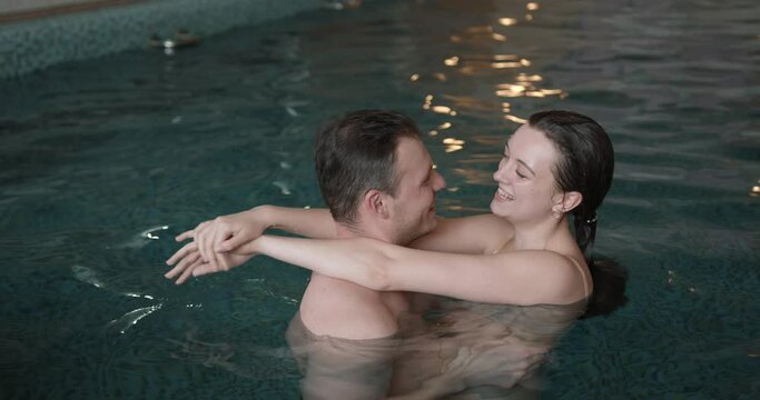 Romantic couple flirting and enjoying in water of indoor swimming pool