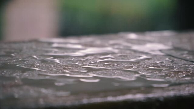Raindrops fall on the wet parapet