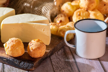 Cheese bread and more, cheese bread, manioc flour cookies and Minas cheese arranged on a rustic wooden surface with accessories, selective focus.