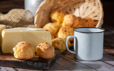 Cheese bread and more, cheese bread, manioc flour cookies and Minas cheese arranged on a rustic wooden surface with accessories, selective focus.