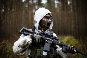 Man in a winter camo suit looking with gun ready.