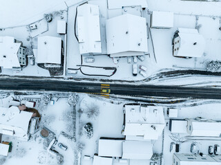Aerial view of town with snow covered houses. Roof tops with snow on residential buildings in...