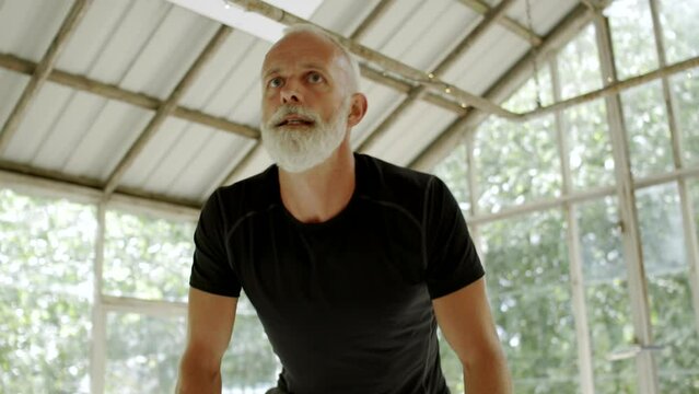 Fit mature man riding on a stationary bike during a exercise session in a gym