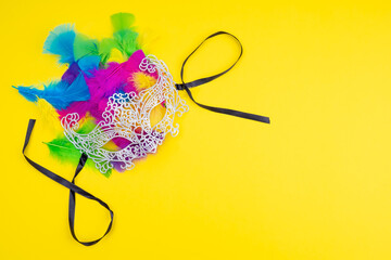 Lacy carnival masks with colored feathers on a yellow background - obrazy, fototapety, plakaty