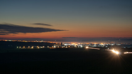 Naklejka premium Illuminated city at late twilight, car light trails