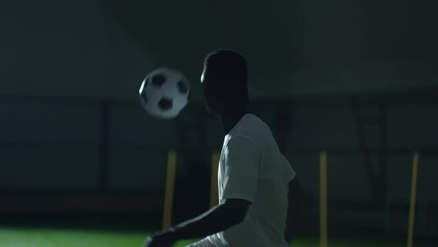 professional soccer player playing football in training center, portrait of african man in motion