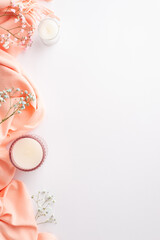 Hello spring concept. Top view vertical photo of pink soft scarf candles in glass holders and gypsophila flowers on isolated white background with empty space