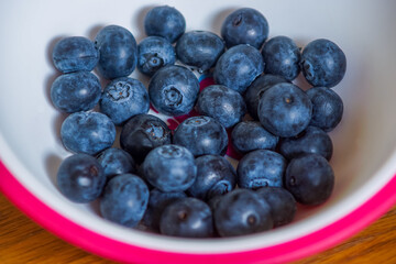 Fresh black grapes in a white and pink bowl on a wooden surface