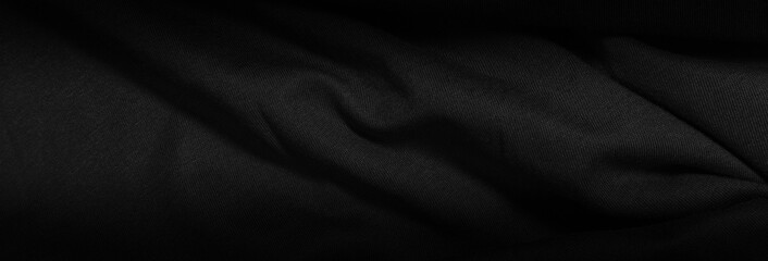 Dark background from a wavy fabric texture. Wide panoramic black background with space for design....