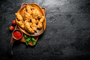 Chicken strips on a plate with parsley and sauce.