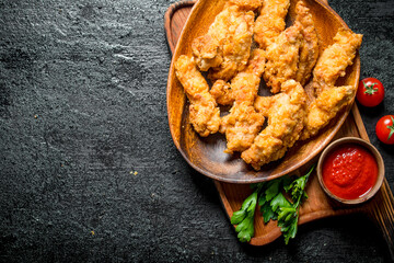 Chicken strips on a plate with parsley and sauce.