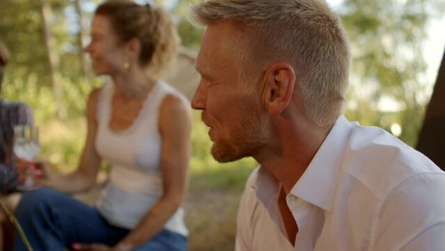 Man toasting marshmallows outside during a summer afternoon campfire with family and friends