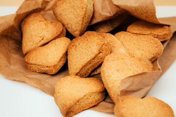 Fototapeta na wymiar Shortbread cookies in the form of hearts in a brown paper bag on a white table. Front view
