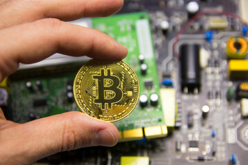 Man's hand holds bitcoin cryptocurrency against the background of a microcircuit