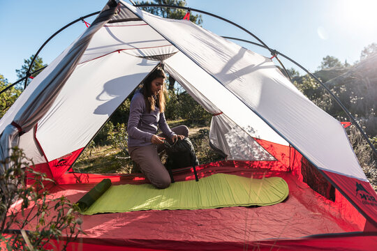 Hispanic woman hiker setting up tent in springtime