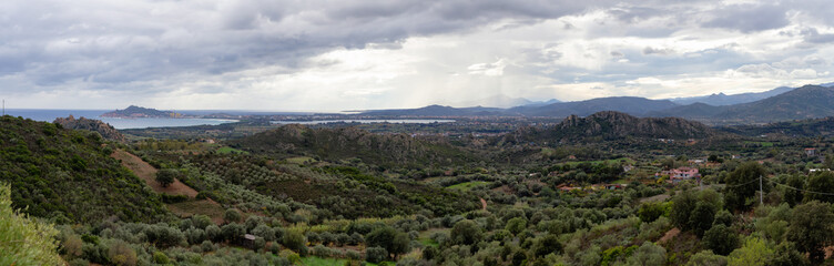 Fototapeta na wymiar Panoramic View of Farm Fields and Town on the Sea Coast. Santa Maria Navarrese, Sardinia, Italy. Cloudy and Rainy Sky.