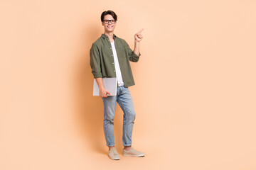 Full length size cadre of young cheerful positive man remote education direct finger point mockup with laptop isolated on beige color background