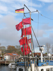 Rote Markierungsfahnen für die Reusen eines Fischers flattern im Wind auf einem Fischerboot im...