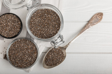 Chia seeds in jar and spoons on white texture wood. Superfood. Antioxidant. Healthy food. Proper nutrition. Diet concept. Place for text. Place to copy. selective focus.