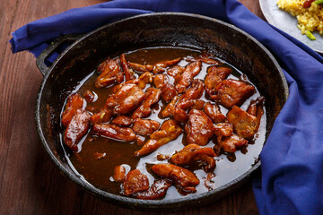 Fried chicken pieces in soy and pad thai sauce in a pan on a blue napkin.