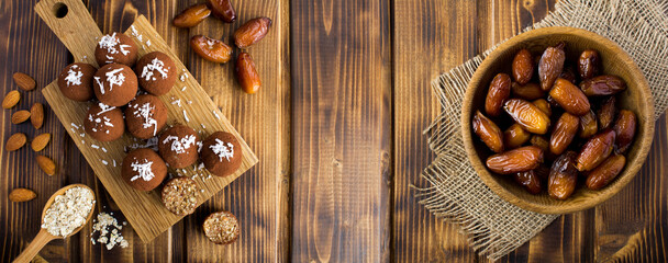 Energy balls with dates, coconut chips, almond and oats cereals on the wooden background. Top view....