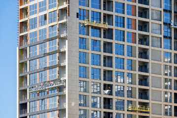 A fragment of the construction of a multi-storey residential building with finishing decorative facade cladding.