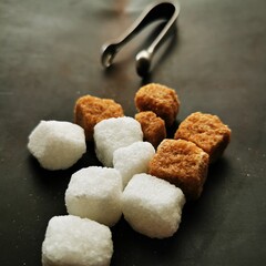 White and brown sugar cubes against a dark background.