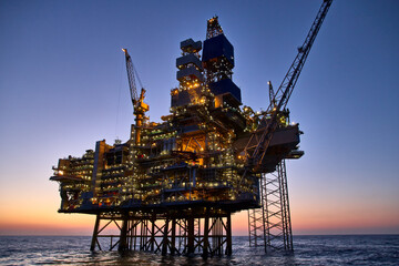 Offshore oil and gas platform in the sea at sunset. 
Jack up rig crude oil production in the North Sea.
