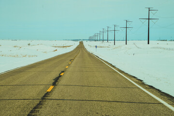 Narrow ribbon of paved highway stretching into the white vast North Dakota landscape.