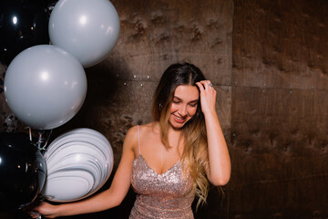 Romantic cute lady with long light hair wearing festive dress looking down and touching hair while...