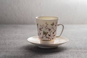Cup and saucer on a grey tablecloth background.