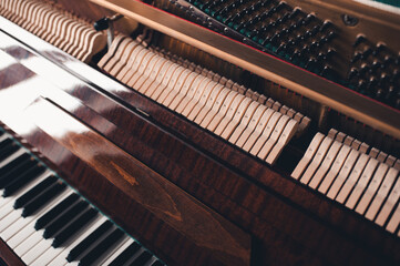 Old vintage acoustic piano inside with hammers and strings close up. Tuning musical instrument. Selective focus.