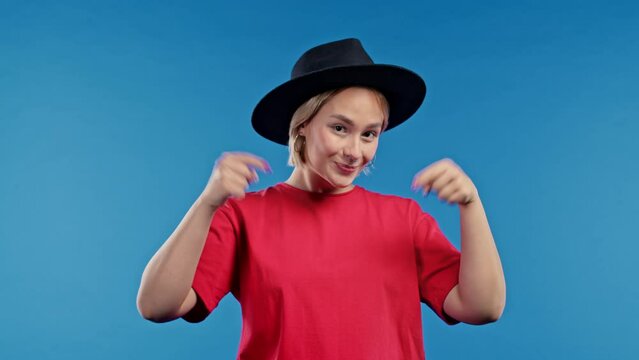 Happy woman pointing down to advertising area. Blue background. Young lady asking to click to subscribe below. Copy space for your commercial idea, promotional content.